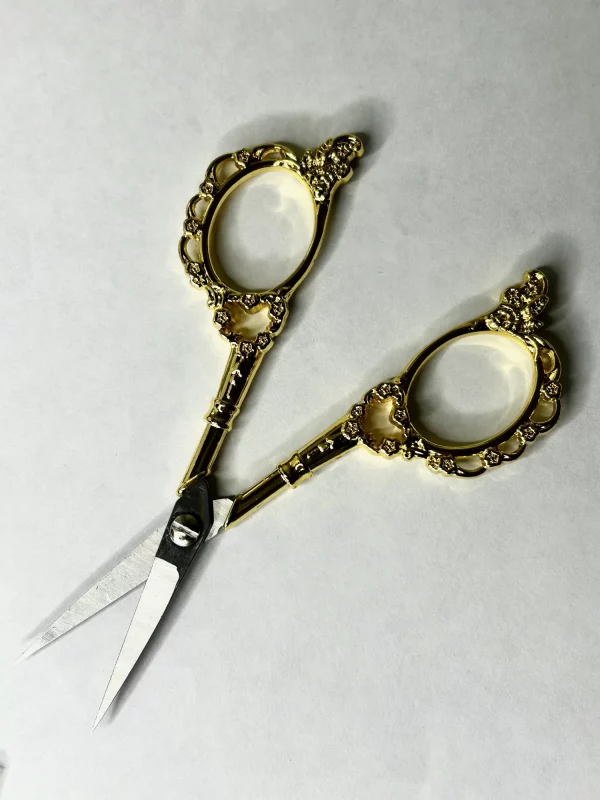 Ciseaux de précision 11 cm vintage motif floral posés sur tissu, prêts pour couture et broderie